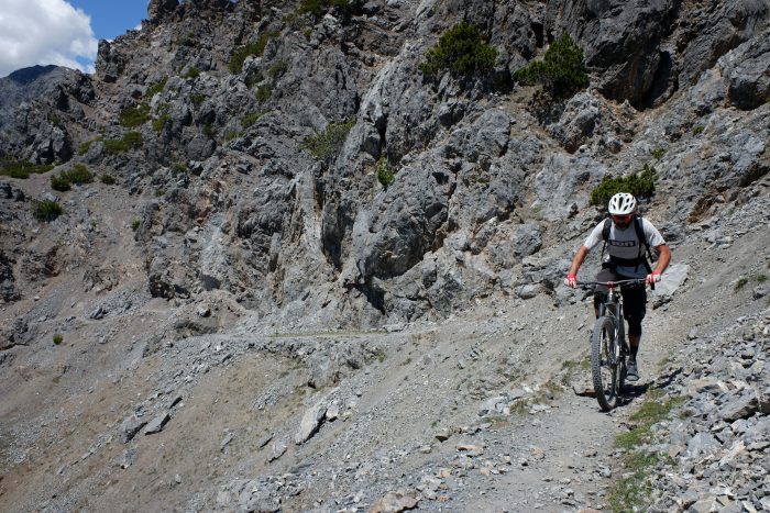 A tourist mountain biking on a challenging trail in the Alps. Sustainable travel in Italy.