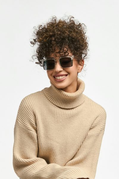 A woman wearing a beige turtleneck sweater and sunglasses